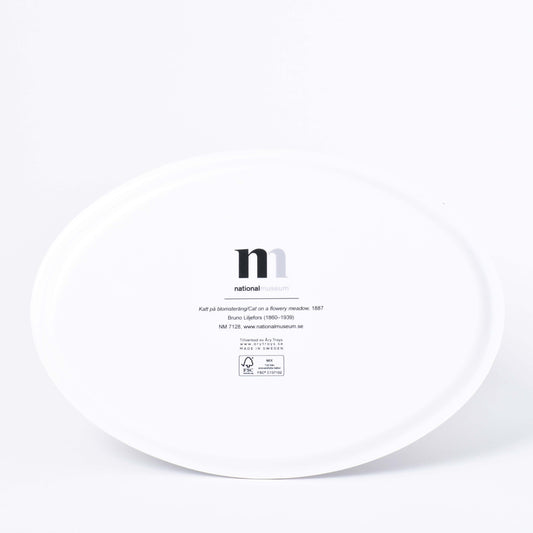 Vit baksida av oval bricka med motiv av Bruno Liljefors Katt på blomsteräng