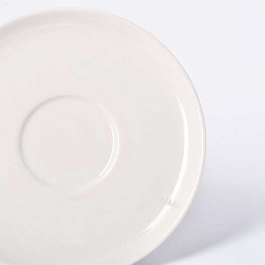 Runt sandfärgat fat till kopp med NM& monogram ingraverat i kanten i design av Carina Seth Andersson