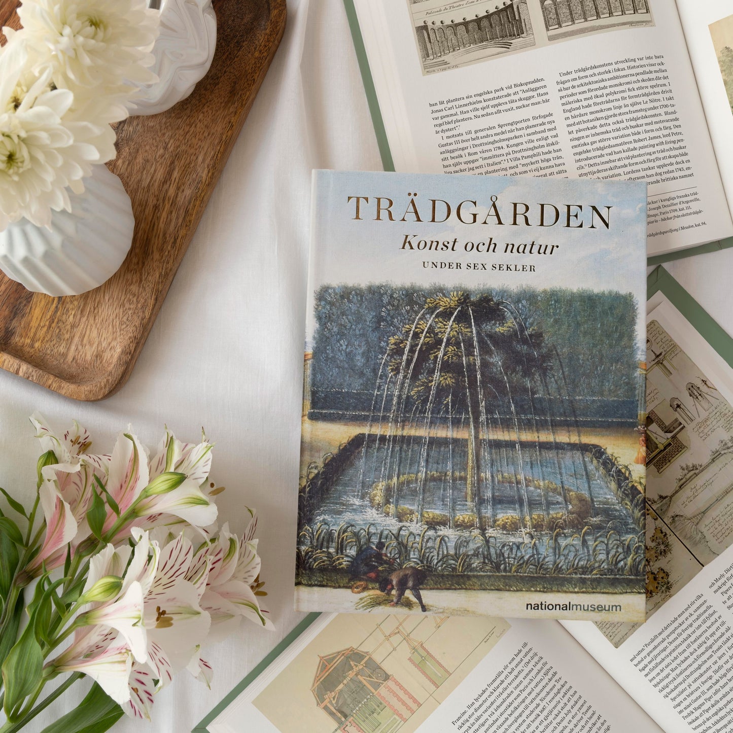 Stilleben med utställningskatalogen Trädgården och blommor