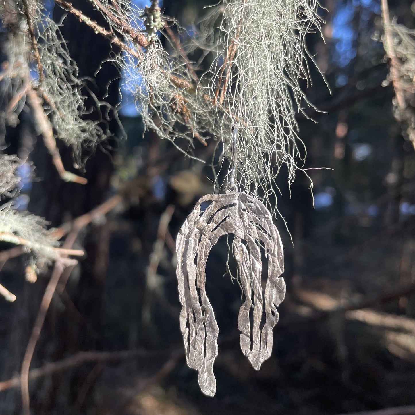 örhänge från Ovrebruket inspirerat av John bauer som hänger i ett träd i skogen