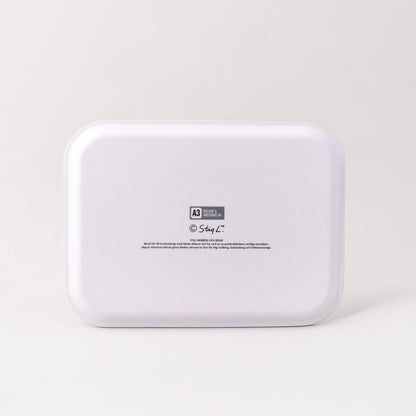 Vit baksida av bricka med Stig Lindbergs signatur