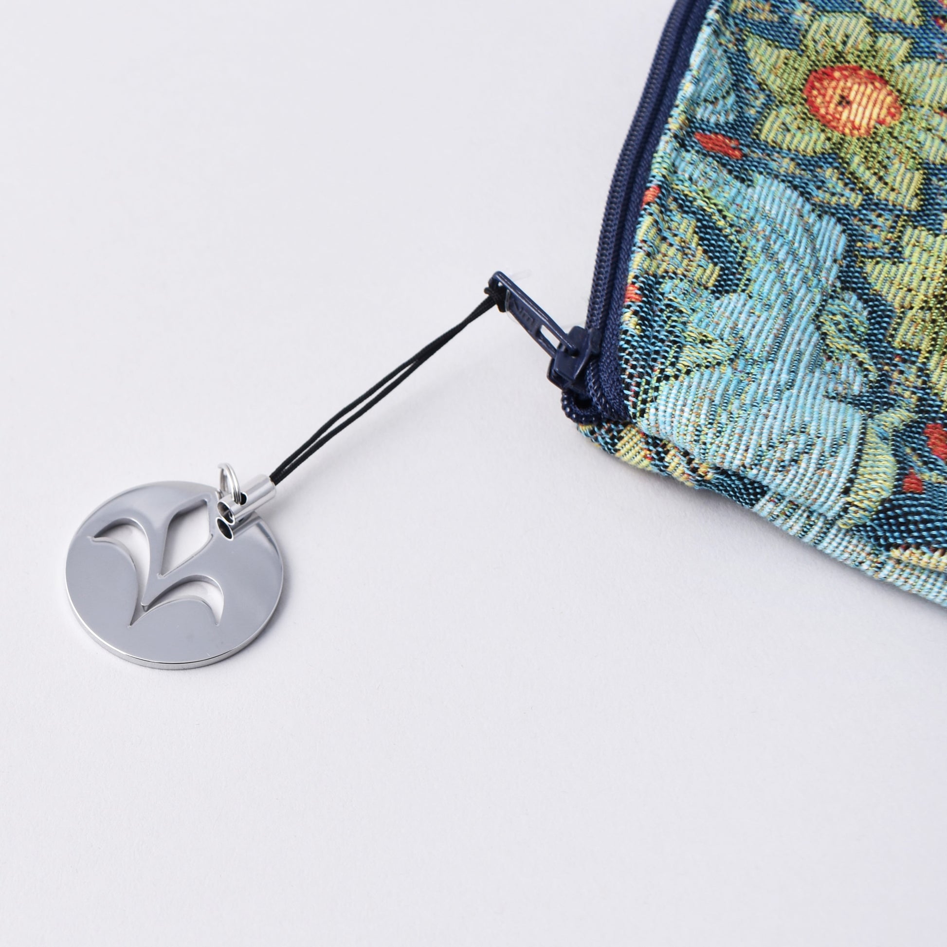 Detalj på dragkedja med silveremblem på necessär inspirerad av William Morris
