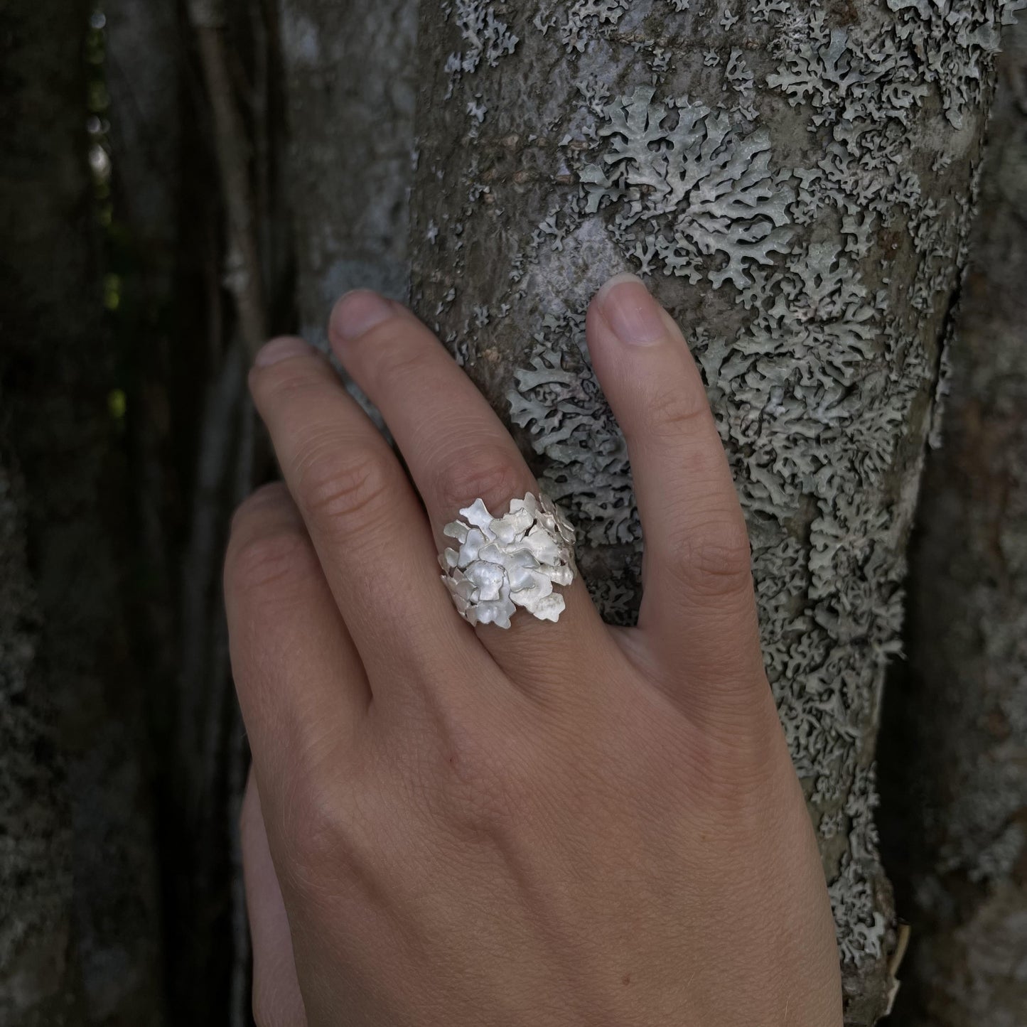handgjord silvering inspirerad av skogen på hand som stödjer sig mot ett träd