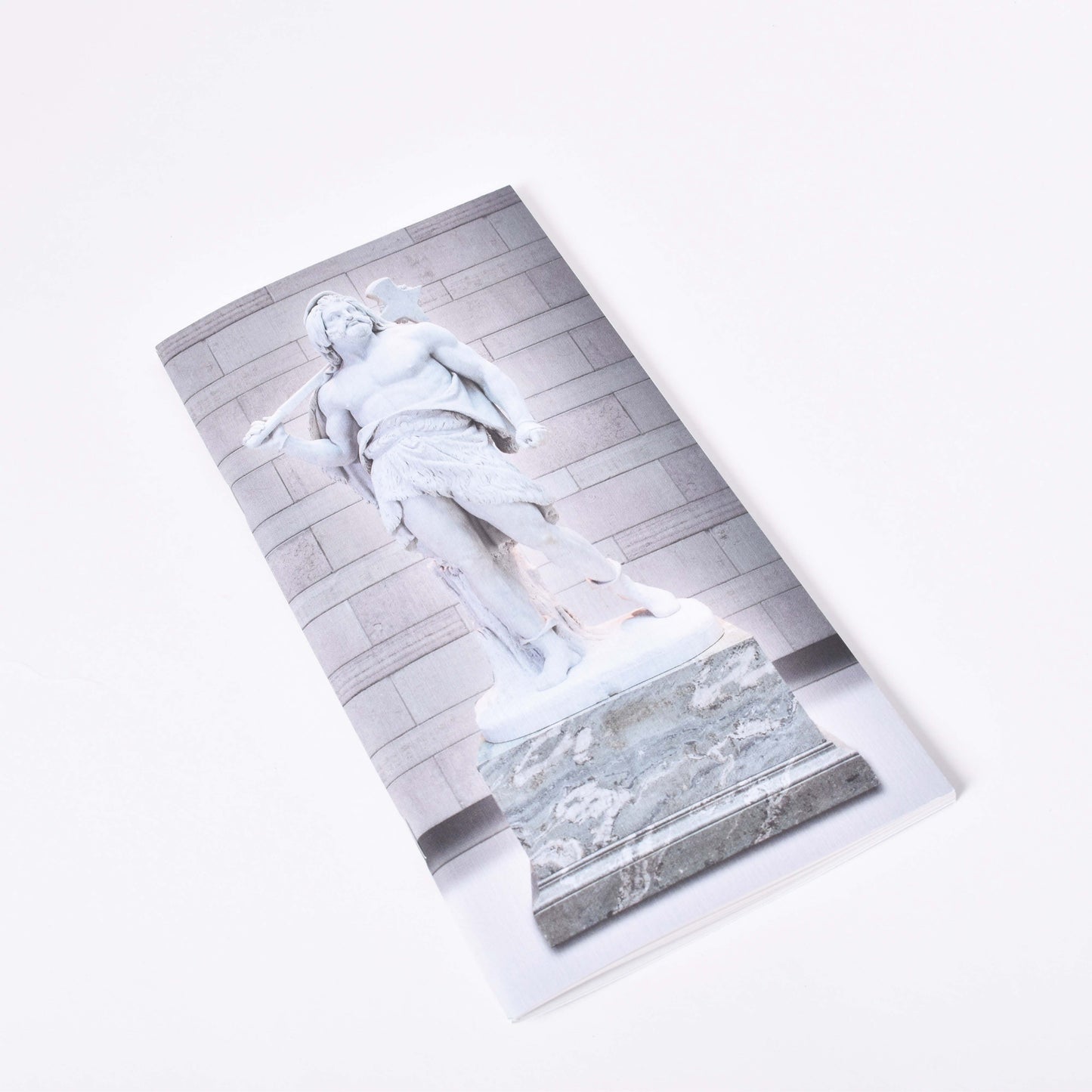 Långsmal anteckningshäfte med omslagsmotiv av Bengt Erland Fogelbergs skulptur Tor