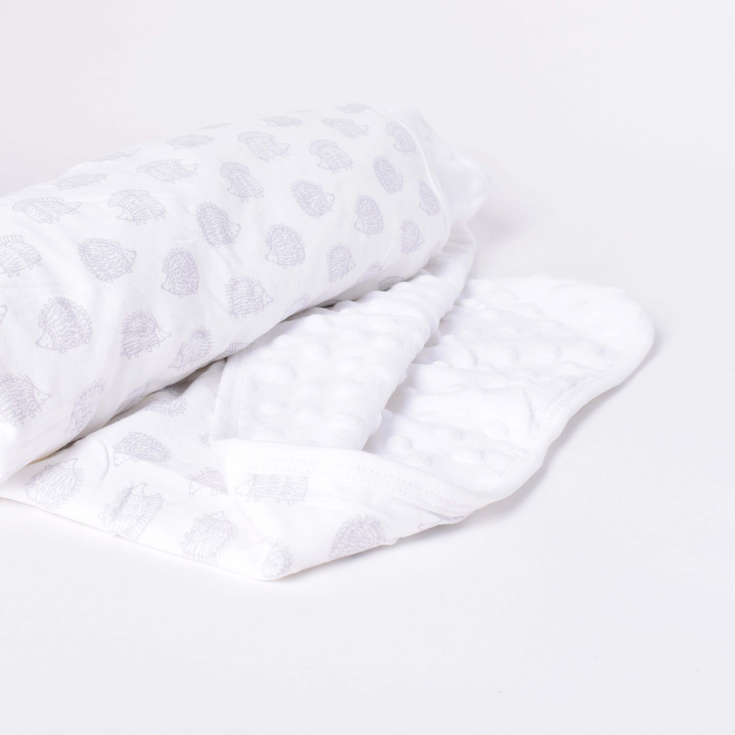 Vit babyfilt med motiv av grå igelkottar i mönsterdesign av Lisa Larson