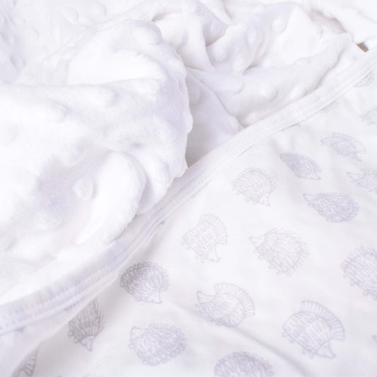 Vit babyfilt med ena sidan mjukt fleecefoder och andra sidan med motiv av igelkottar i mönsterdesign av Lisa Larson
