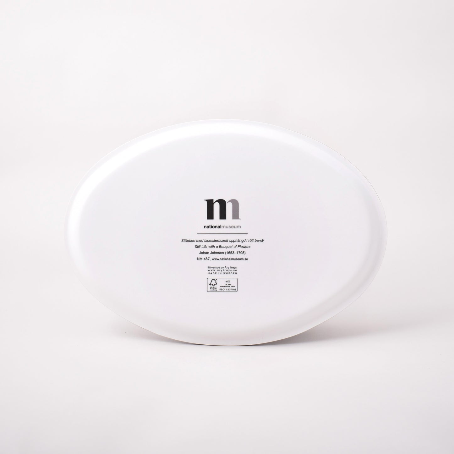 Vit baksida av oval bricka med motiv av Johan Johnsens Stilleben med blomsterbukett