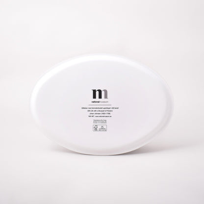 Vit baksida av oval bricka med motiv av Johan Johnsens Stilleben med blomsterbukett