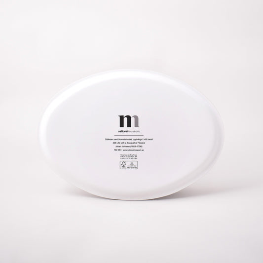 Vit baksida av oval bricka med motiv av Johan Johnsens Stilleben med blomsterbukett