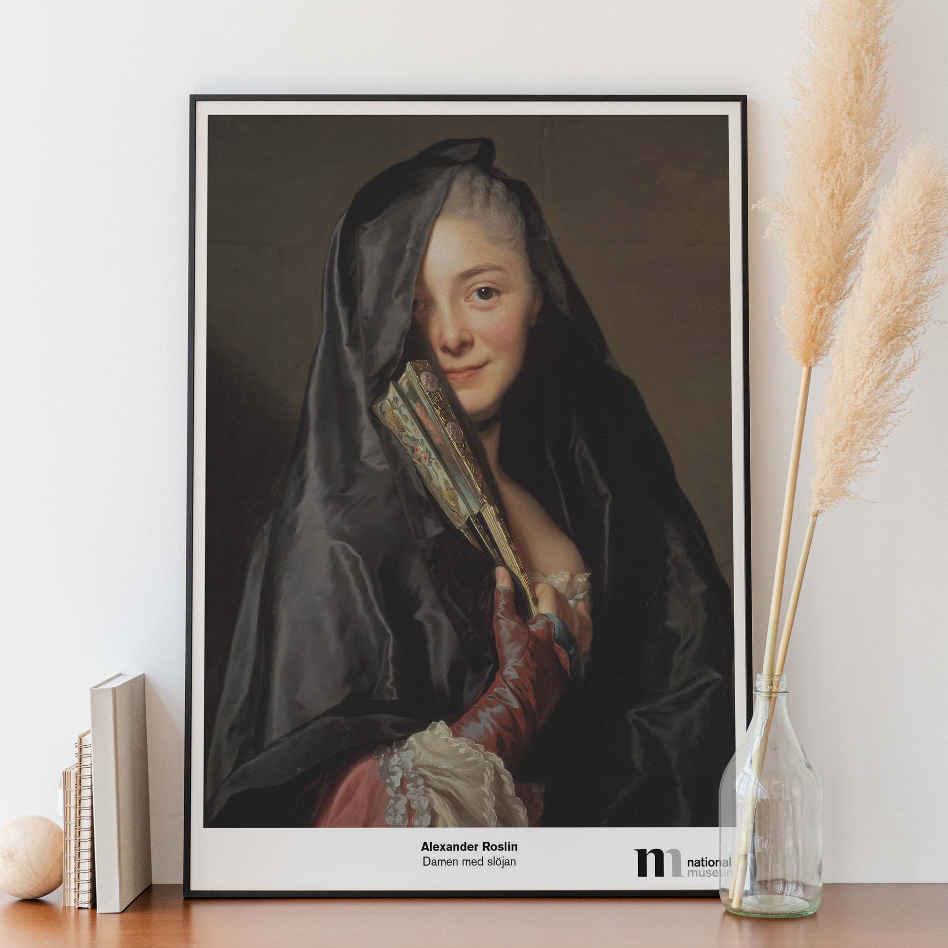 poster med damen i slöjan i svart ram på en bänk