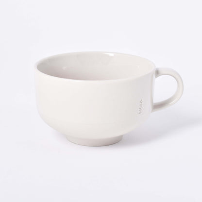 Sandfärgad kopp med öra och NM& monogram ingraverat i mitten i design av Carina Seth Andersson