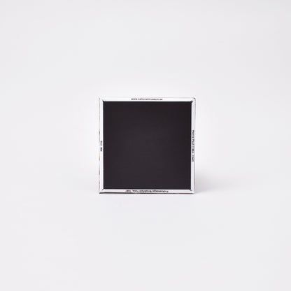 Baksida av kvadratisk magnet med titeln på konstverket frukostdags