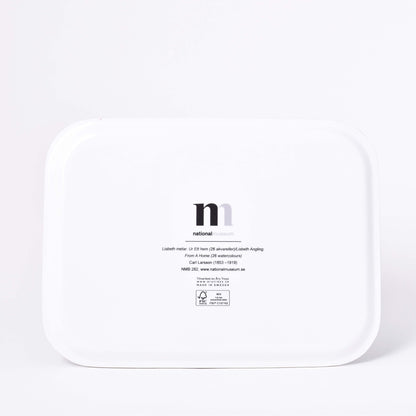 Vit baksida av rektangulär bricka med motiv av Carl Larssons Frukost under stora björken