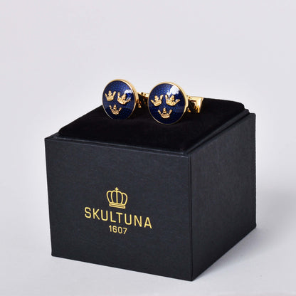 Skultuna manschettknappar med guldpläterad dekor av en variant av riksvapnet Tre Kronor mot kungsblå emalj