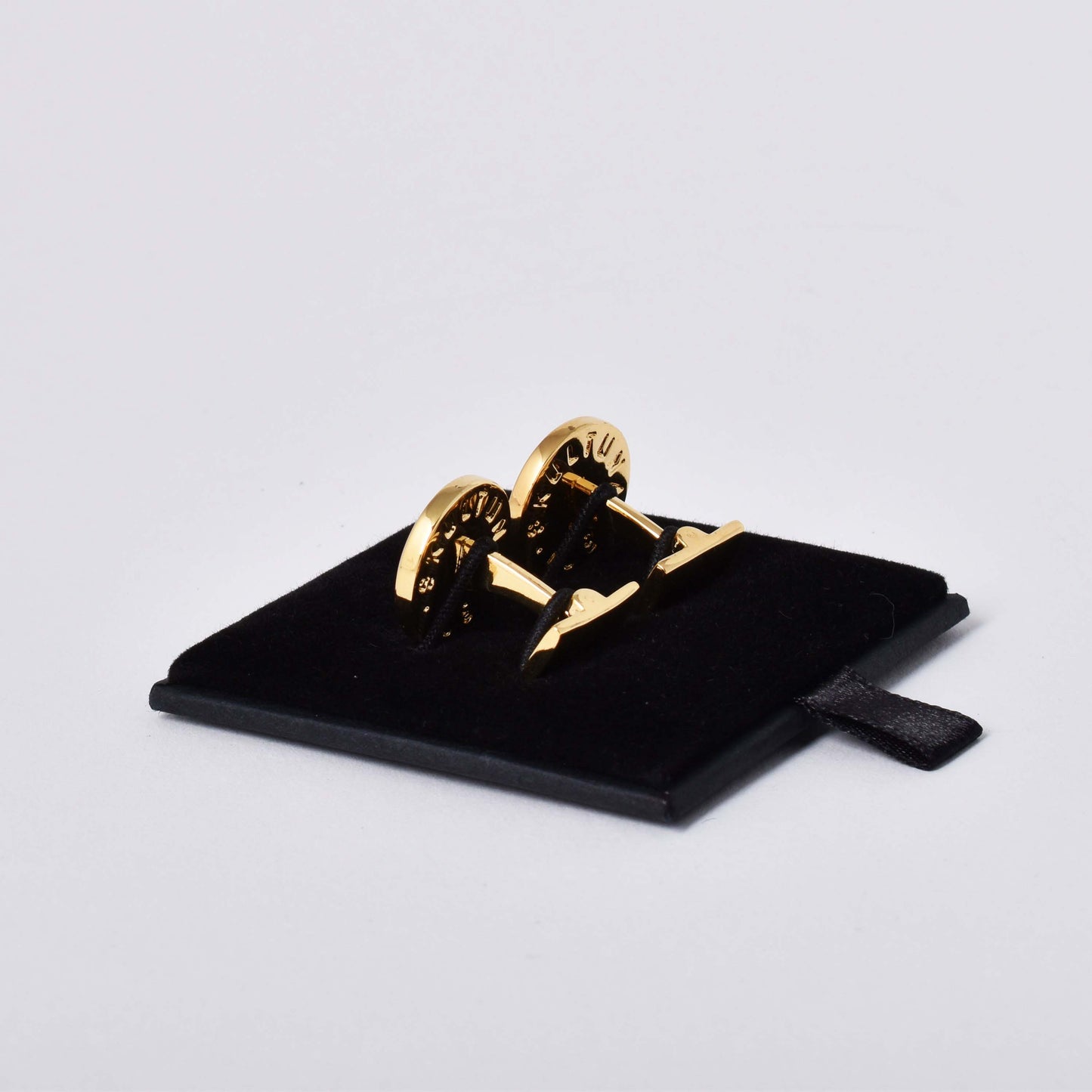 Baksida av Skultuna manschettknappar med guldpläterad dekor av en variant av lilla riksvapnet Tre Kronor mot kungsblå emalj