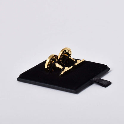 Baksida av Skultuna manschettknappar med guldpläterad dekor av en variant av lilla riksvapnet Tre Kronor mot kungsblå emalj