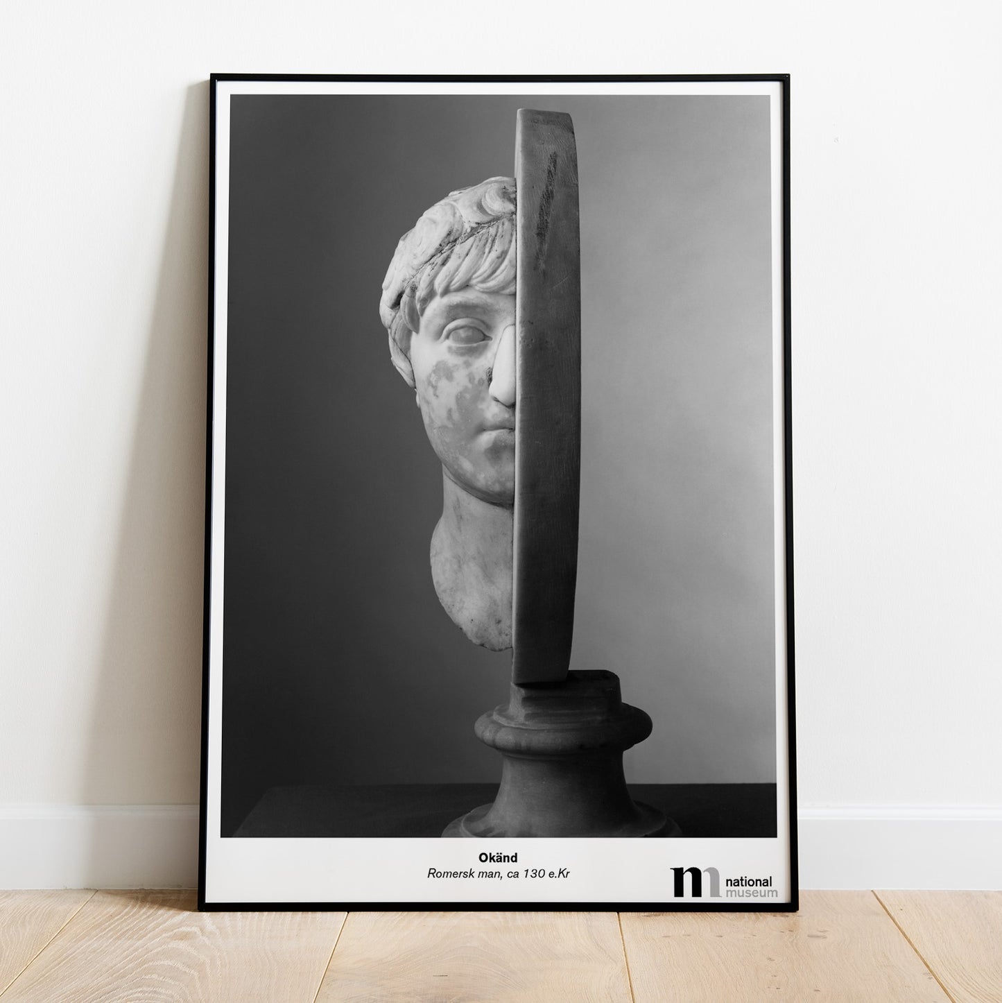 Svartvit poster med skuptur från NAtionalmuseum i svart ram lutad mot en vägg