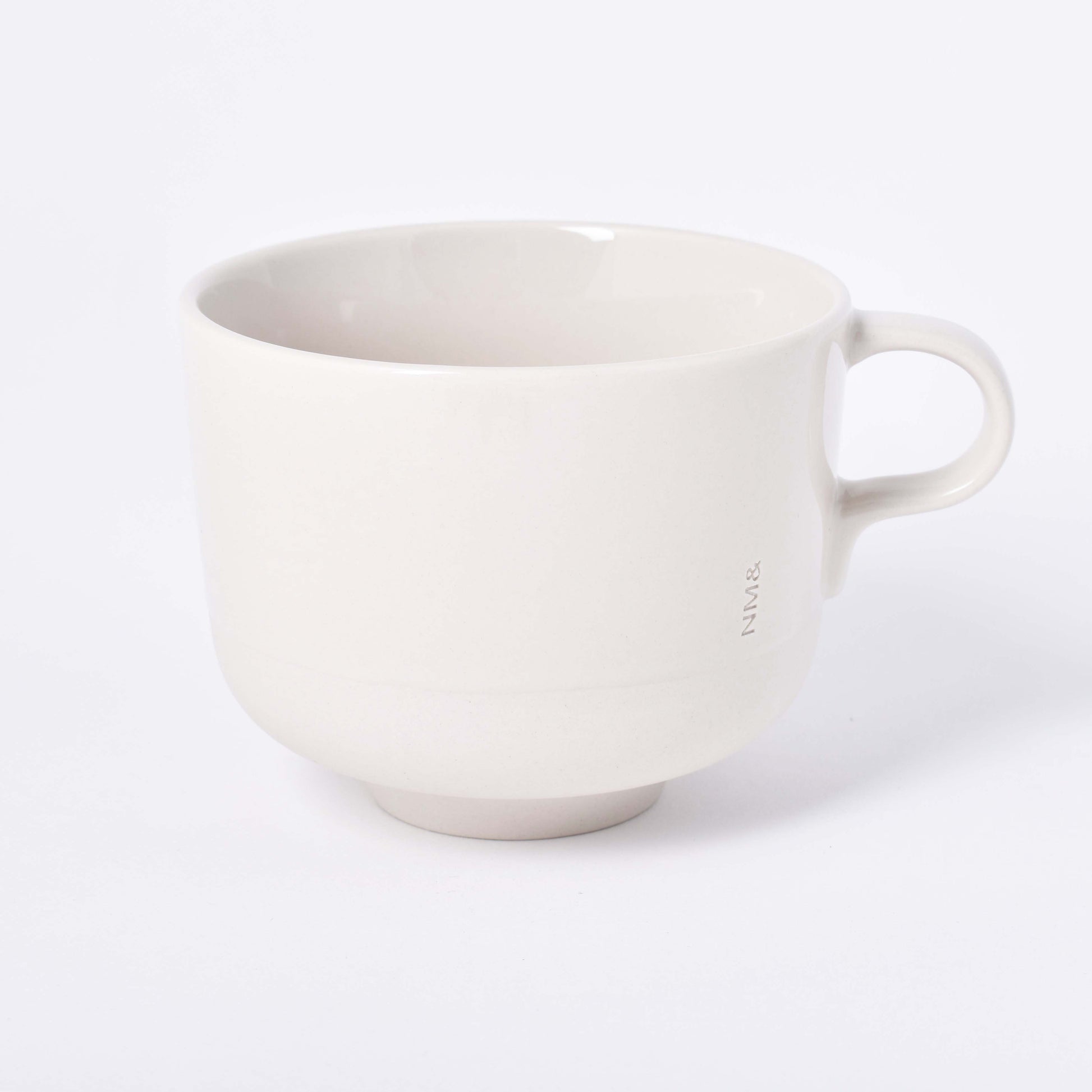 Sandfärgad tekopp med öra och ingraverat NM& monogram i design av Carina Seth Andersson