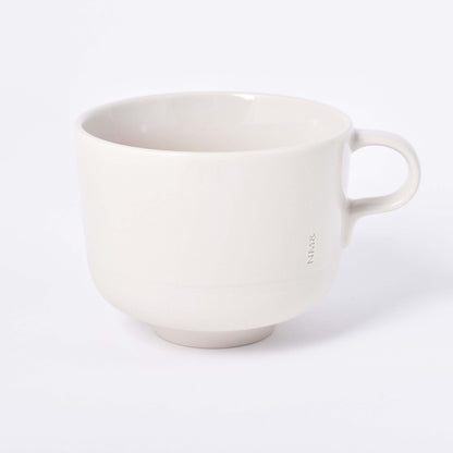 Sandfärgad tekopp med öra och ingraverat NM& monogram i design av Carina Seth Andersson